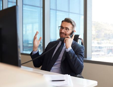 man with glasses smiling and talking by phone