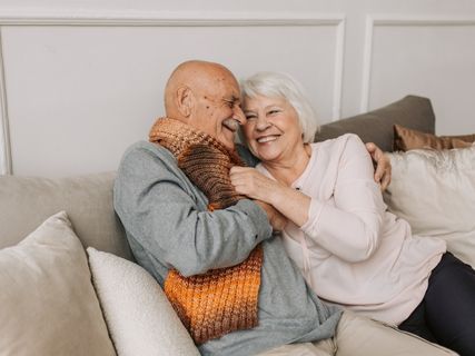 elderly couple smiling on a sofa